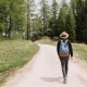 full-length-portrait-from-back-male-traveler-exploring-summer-forest-vacation